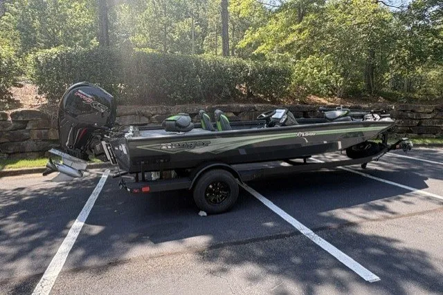 Slide: The Image of 2027 Ranger RT198P boat parked in a sunny lot, surrounded by greenery. - 1