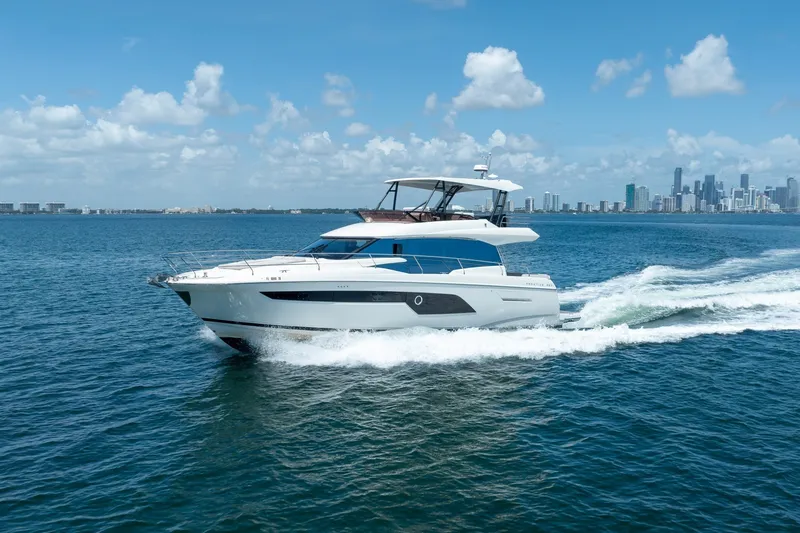 Slide: The Image of Luxury 2020 Prestige 520 yacht cruising on blue ocean near city skyline. - 8