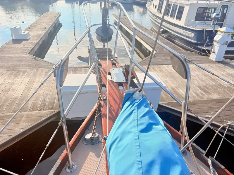 Slide: The Image of Bow of a boat with a blue cover, docked at a wooden pier in a marina. - 10