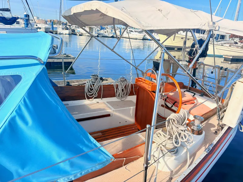 Slide: The Image of A 1979 Shannon 38 sailboat docked in a marina, featuring blue and white covers. - 7