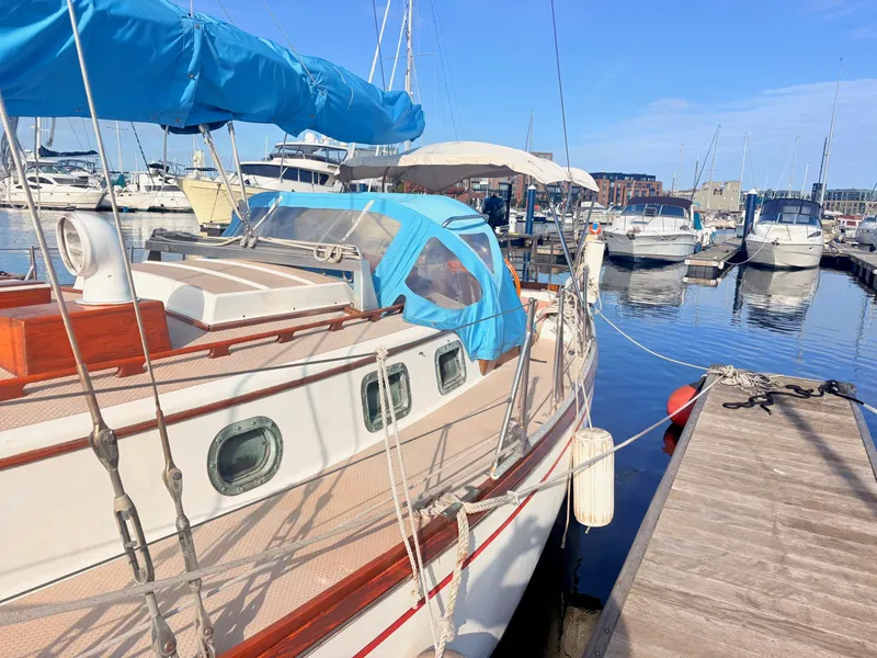 Slide: The Image of A 1979 Shannon 38 sailboat docked, featuring a blue cover and wooden details. - 6