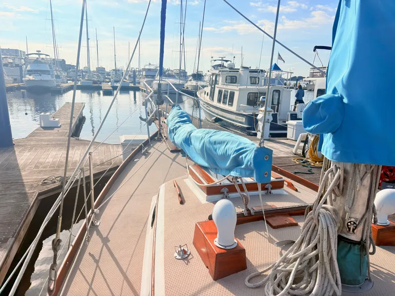 Slide: The Image of A sailboat in a marina with blue covers and wooden details, surrounded by other boats. - 9