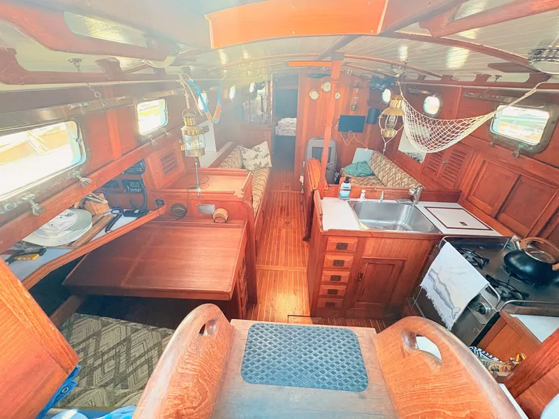Slide: The Image of Interior of a 1979 Shannon 38 with wooden finish, kitchen, dining table, and cozy seating areas. - 17