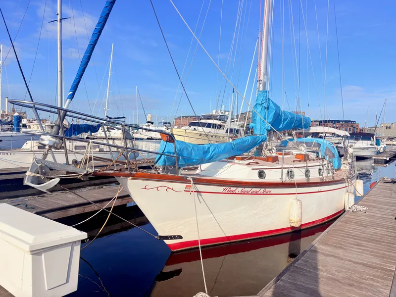 Slide: The Image of A 1979 Shannon 38 sailboat docked in a marina. It features a white hull design with blue covers. - 0