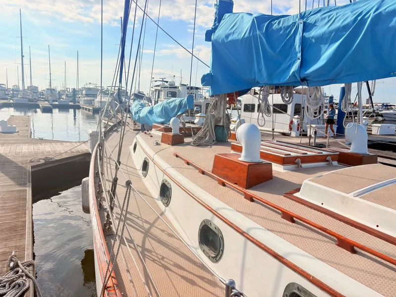 Slide: The Image of A 1979 Shannon 38 sailboat docked in a marina, featuring blue sail covers and wooden details. - 8