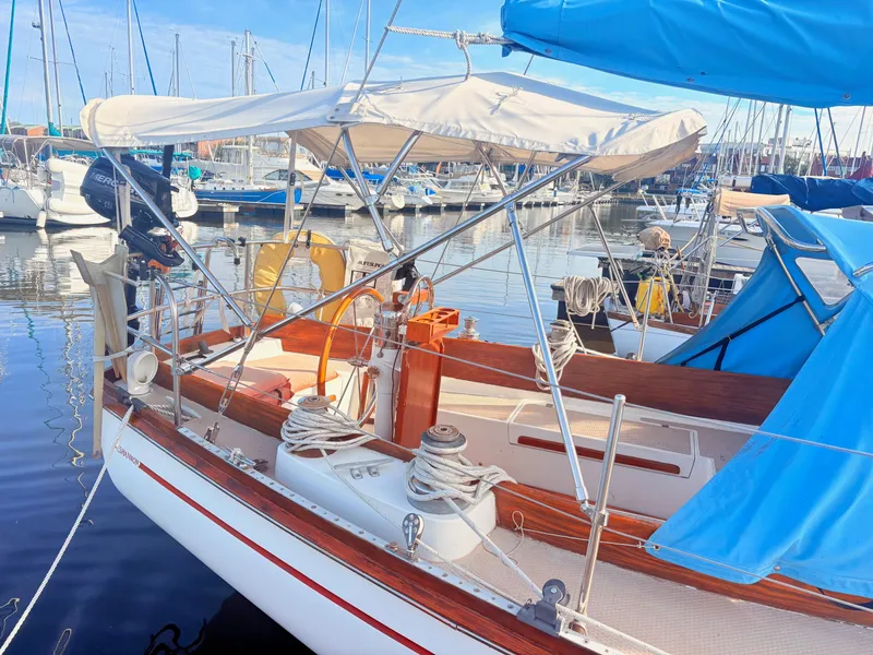 Slide: The Image of A 1979 Shannon 38 sailboat docked in a marina. It features a white canopy and wooden details. - 4