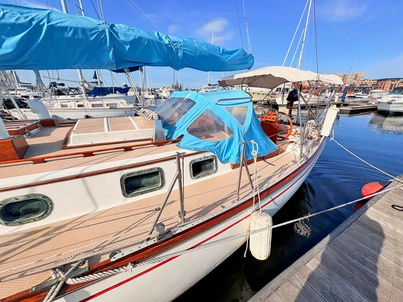Slide: The Image of A 1979 Shannon 38 sailboat docked in a marina, featuring a blue cover and wooden accents. - 35