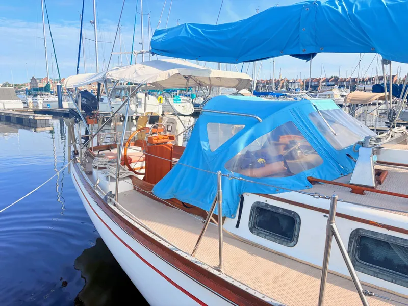 Slide: The Image of A 1979 Shannon 38 sailboat docked in a marina, featuring a blue canopy and wooden details. - 3