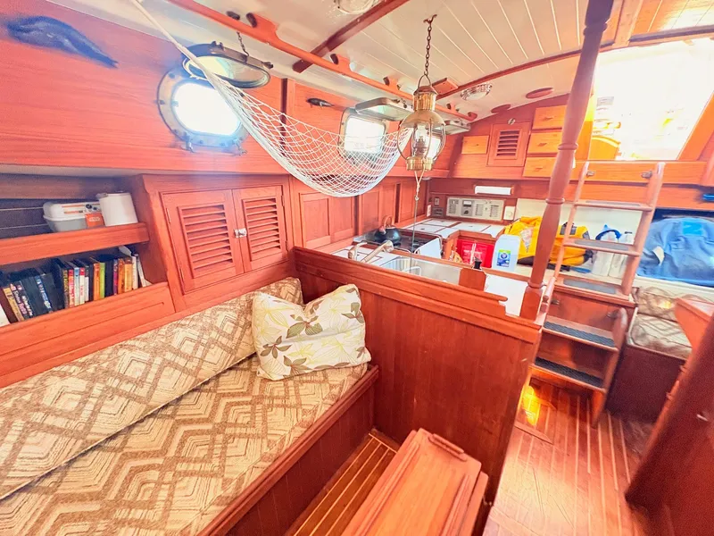 Slide: The Image of Interior of a 1979 Shannon 38 with wooden furnishings, a sofa, bookshelves, and a hammock. - 30