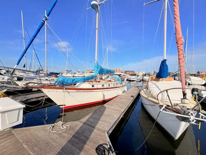 Slide: The Image of A 1979 Shannon 38 sailboat docked in a sunny marina, surrounded by other boats. - 36