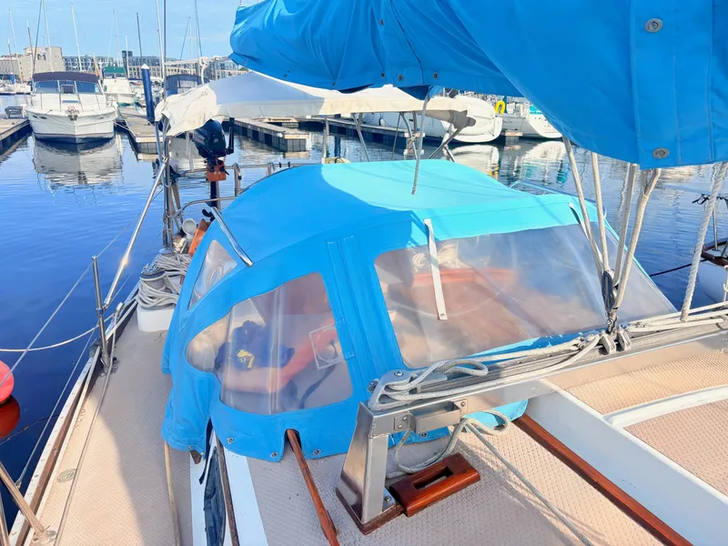 Slide: The Image of A 1979 Shannon 38 sailboat with blue canvas cover docked at a marina. - 13