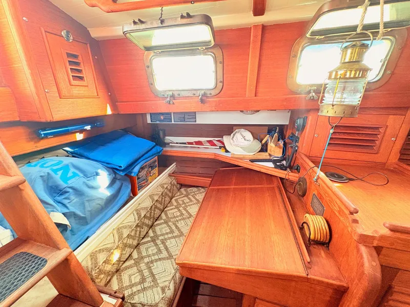 Slide: The Image of The interior of a 1979 Shannon 38 features a cozy cabin with wood paneling and a table. - 22