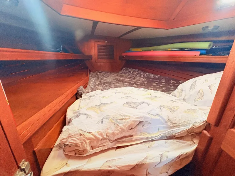 Slide: The Image of The cabin of a 1979 Shannon 38 with a cozy bed and wooden paneling. - 26