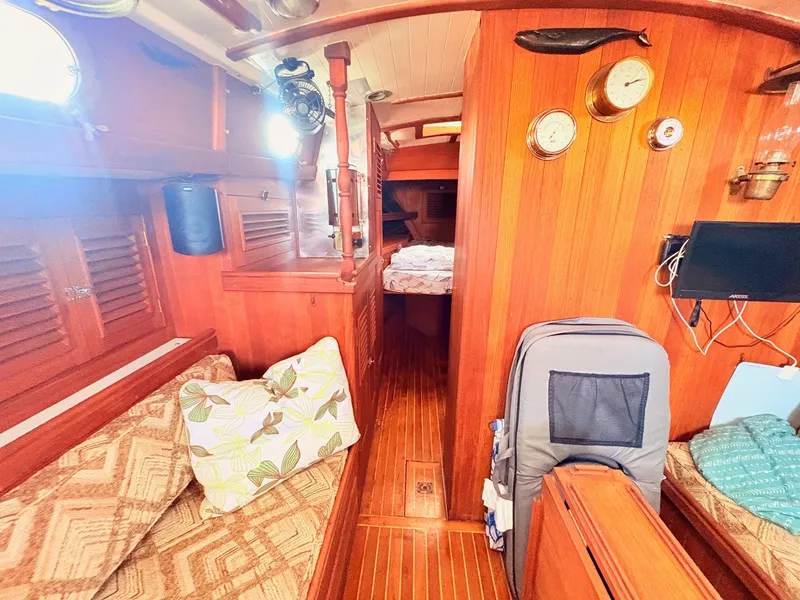 Slide: The Image of Interior of a 1979 Shannon 38 with wooden walls, cozy seating, and a bed in the background. - 24