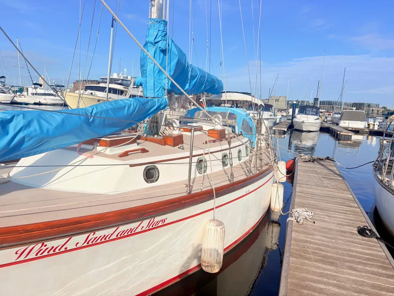 Slide: The Image of A white sailboat with blue sail covers docked at a wooden pier in a marina. - 5