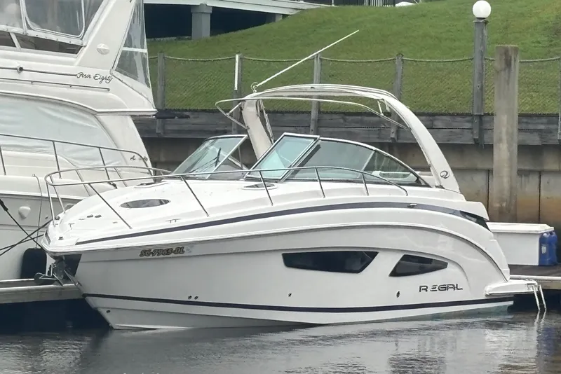 Slide: The Image of 2018 Regal 33 XO boat docked at marina, sleek design, white exterior. - 1