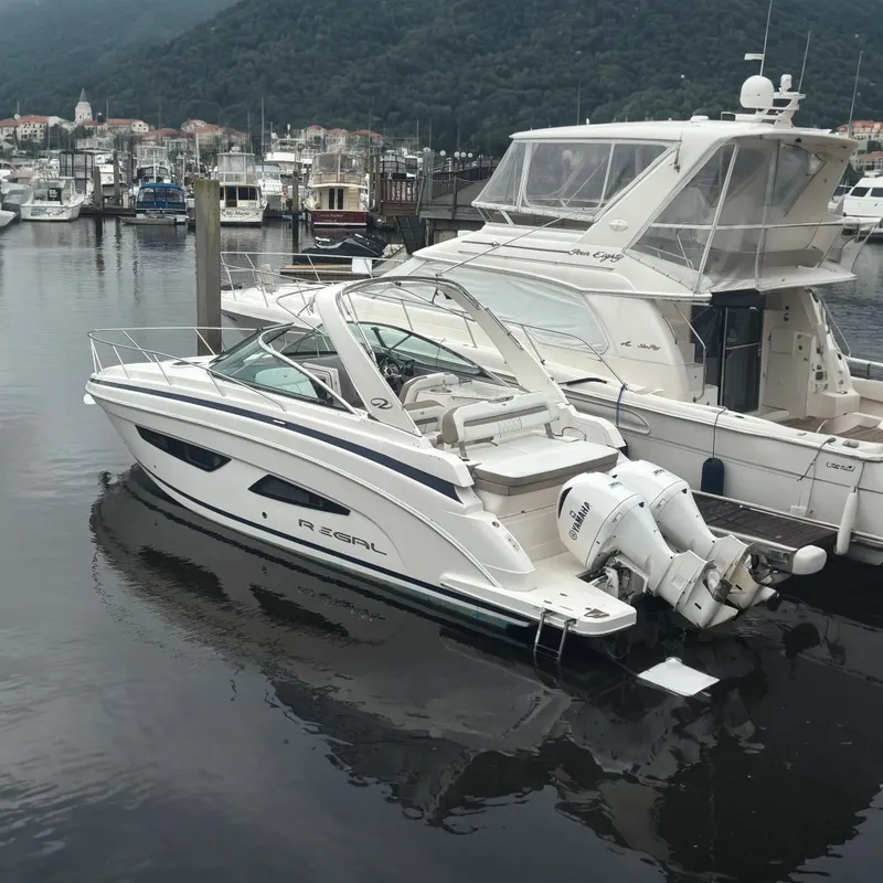 The Image of 2018 Regal 33 XO boat docked in a marina with other vessels. - 0