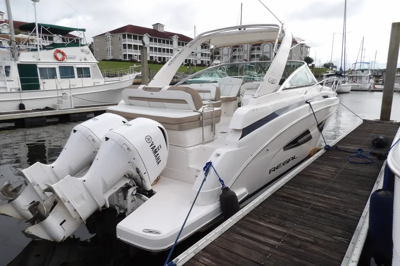 Slide: The Image of 2018 Regal 33 XO boat docked, featuring twin Yamaha outboard engines, in a marina setting. - 4
