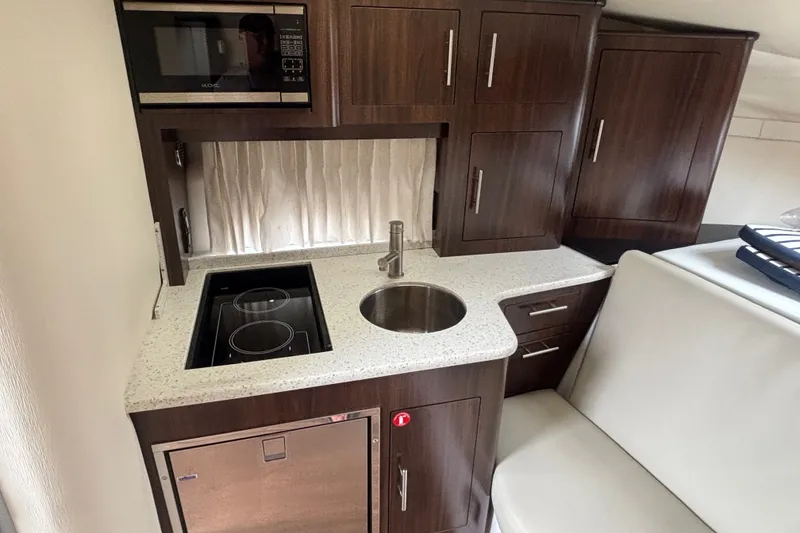 Slide: The Image of Compact kitchen area in 2018 Regal 33 XO boat with modern appliances and wood cabinetry. - 28