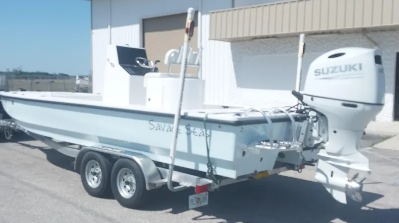 Slide: The Image of 2024 Savage Seas Shallow Bay SS22 boat with Suzuki outboard motor on trailer. - 2