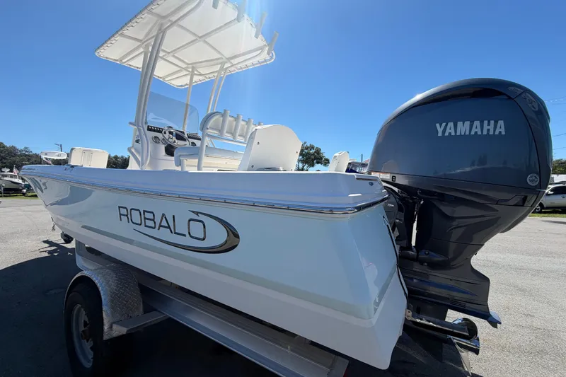 Slide: The Image of 2024 Robalo 206 Cayman boat with Yamaha engine, parked on a trailer under clear blue sky. - 6