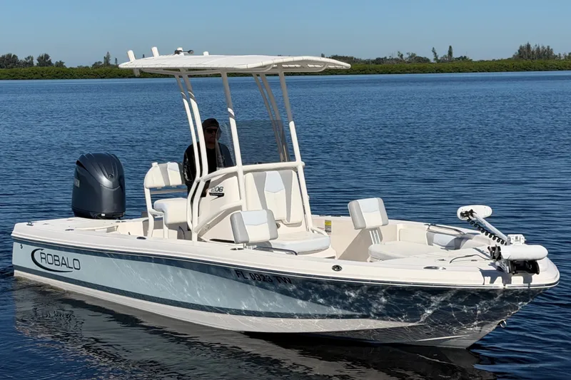 Slide: The Image of A 2024 Robalo 206 Cayman boat on calm water with a white hull and T-top. - 35