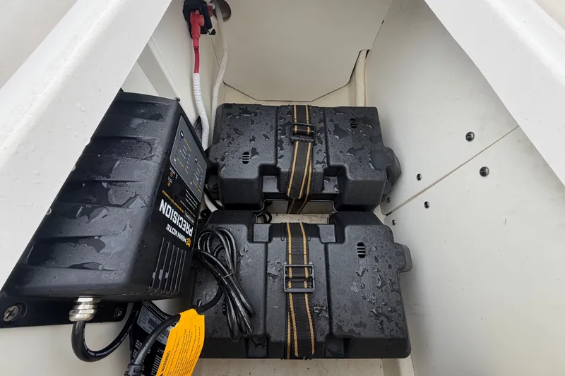 Slide: The Image of The image shows two black battery boxes with straps in a boat storage compartment. - 29