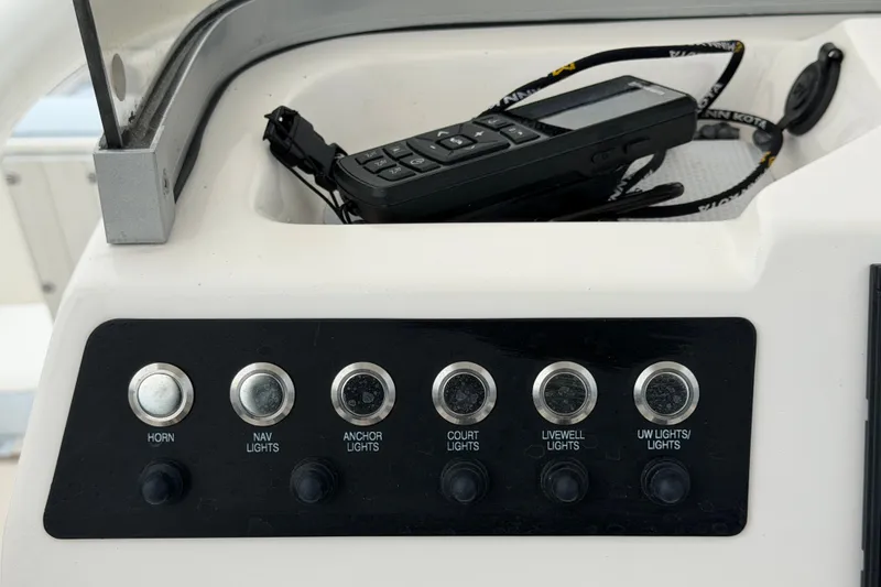 Slide: The Image of Control panel of 2024 Robalo 206 Cayman boat with various switches and a handheld device. - 19