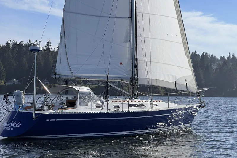 Slide: The Image of 1981 Nordic Boats 40 sailboat with white sails on a calm lake. - 1