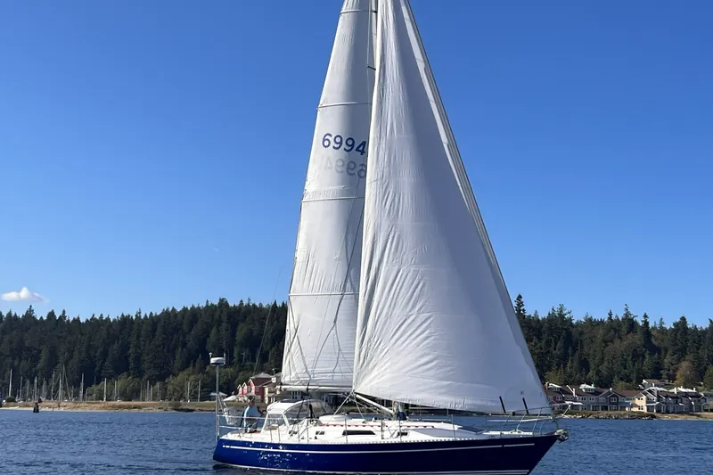 Slide: The Image of 1981 Nordic Boats 40 sailboat on calm water with forested shoreline background. - 2