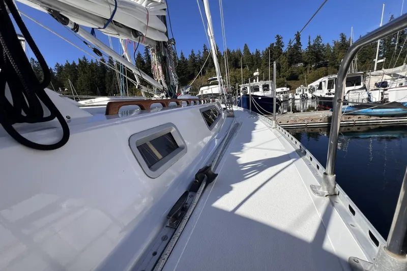 Slide: The Image of 1981 Nordic Boats 40 sailboat docked in a marina, surrounded by trees and clear blue sky. - 15