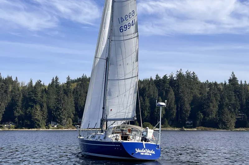 Slide: The Image of 1981 Nordic Boats 40 sailboat on calm water, surrounded by forested shoreline. - 3