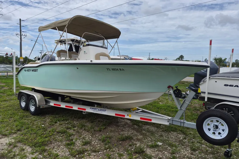 The Image of 2016 Key West 219 FS boat on trailer, parked outdoors under cloudy sky. - 0