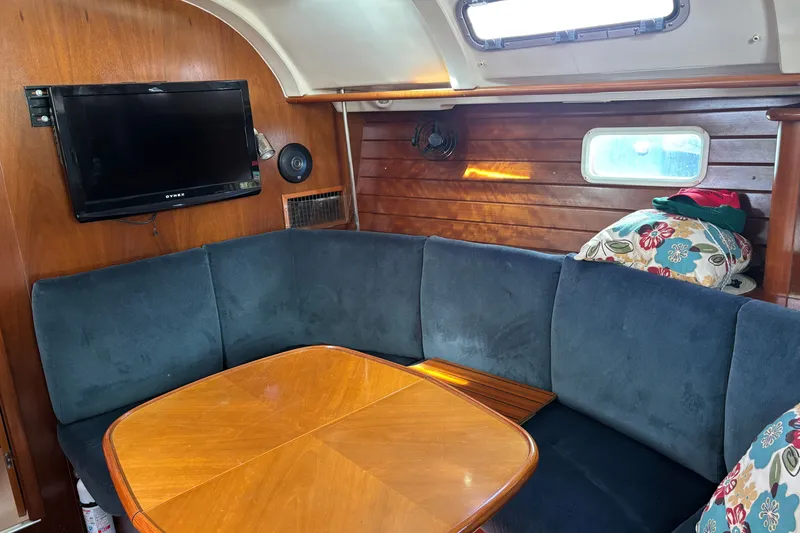 Slide: The Image of Interior of 1999 Beneteau 381 sailboat with cozy seating, wooden table, and mounted TV. - 17