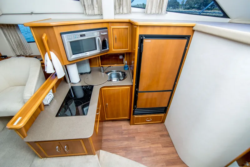 Slide: The Image of 2006 Carver 33 Super Sport yacht kitchen with microwave, sink, and refrigerator. - 24