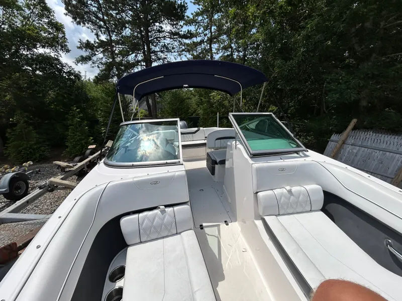 Slide: The Image of A 2018 Regal 23 OBX boat with white upholstery and a blue canopy, surrounded by trees. - 16