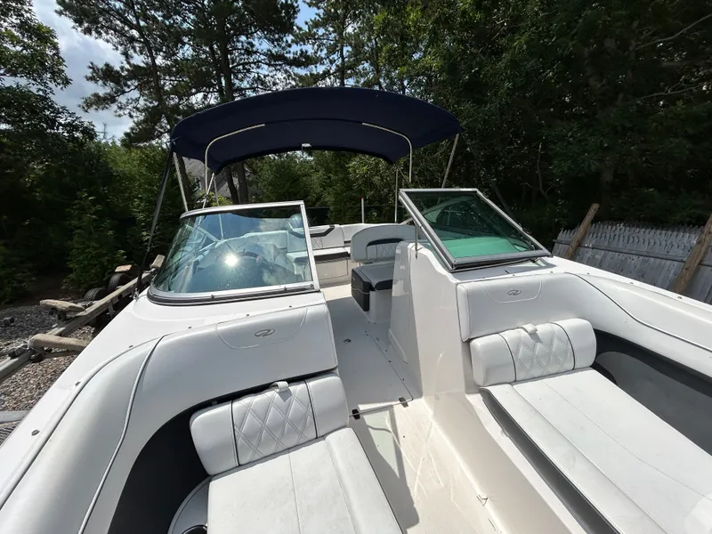 Slide: The Image of A 2018 Regal 23 OBX boat with white interior and blue canopy, surrounded by trees. - 19