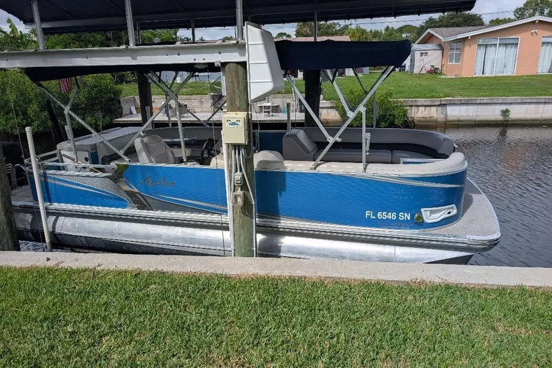 Slide: The Image of 2019 Avalon 2485LSZ pontoon boat docked in a canal under a covered structure. - 2
