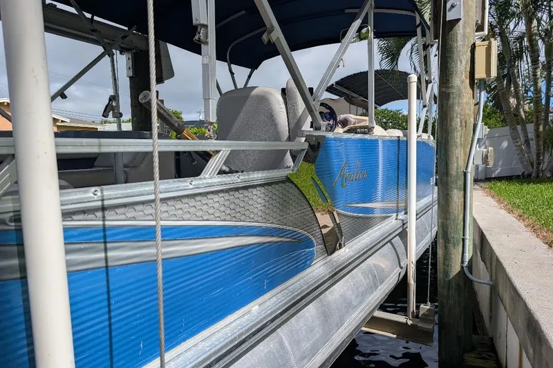 Slide: The Image of 2019 Avalon 2485LSZ pontoon boat docked, featuring blue exterior and canopy. - 6