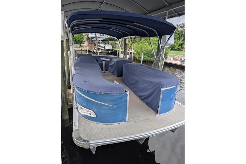 Slide: The Image of 2019 Avalon 2485LSZ pontoon boat with blue covers docked under a canopy. - 7