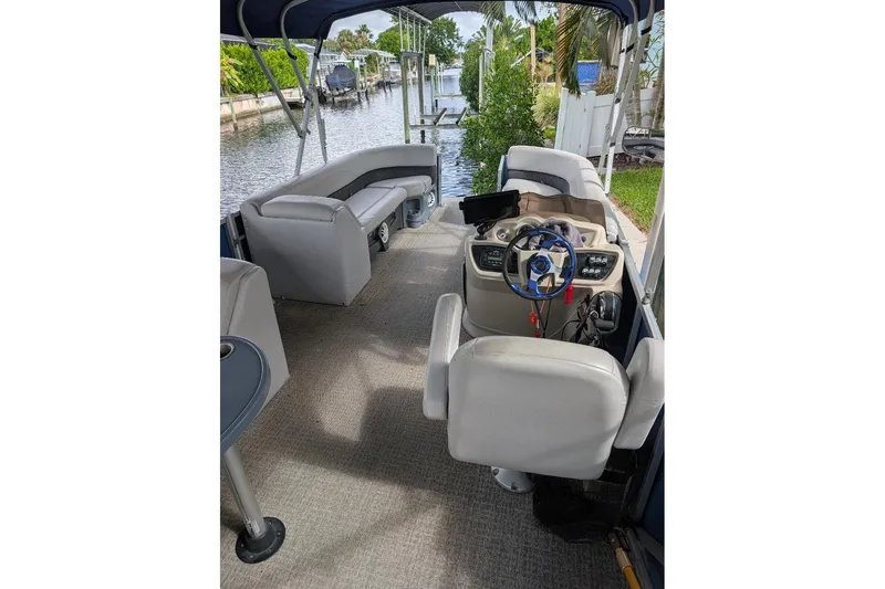 Slide: The Image of 2019 Avalon 2485LSZ pontoon boat interior with seating and steering console by a canal. - 9
