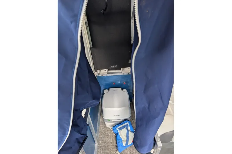 Slide: The Image of 2019 Avalon 2485LSZ interior with portable toilet and blue privacy curtain. - 12
