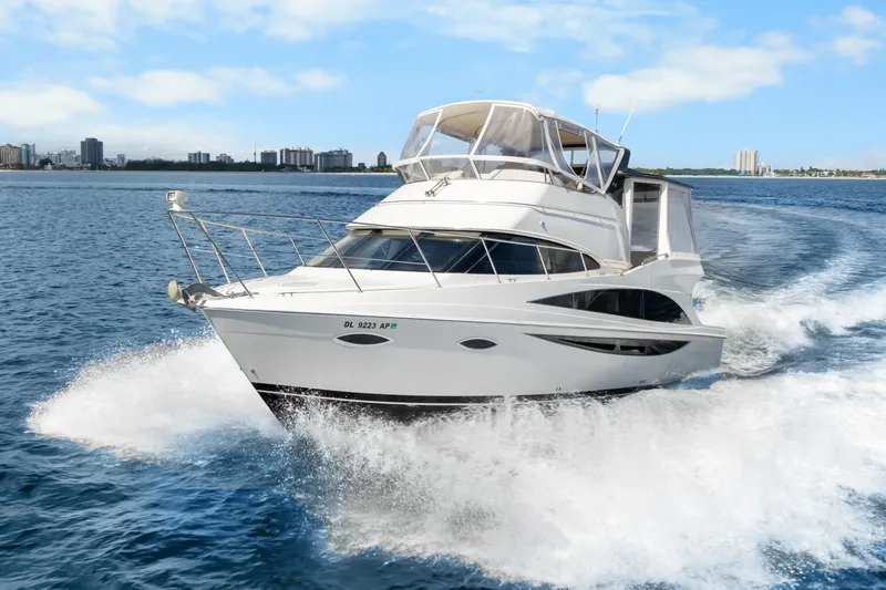 Slide: The Image of 2012 Carver 41 Cockpit Motor Yacht cruising on open water with city skyline backdrop. - 9