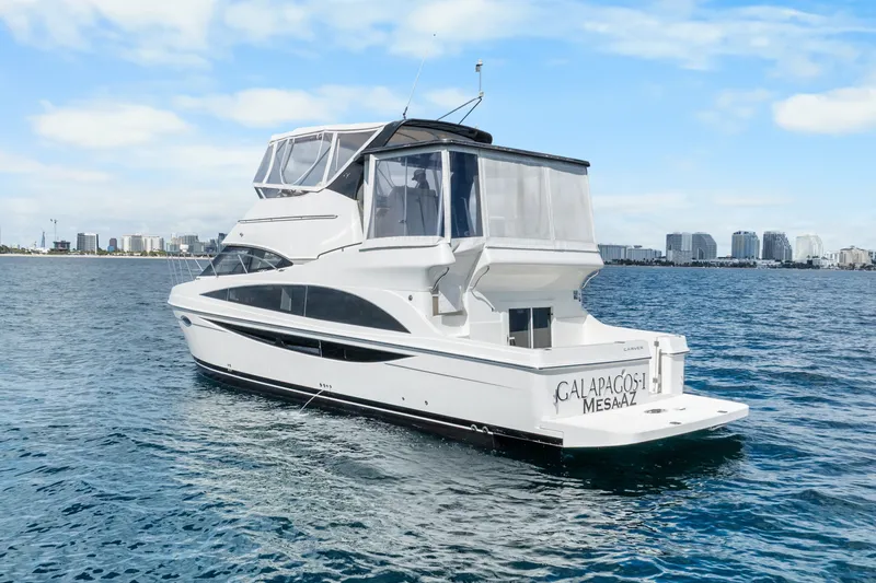 Slide: The Image of 2012 Carver 41 Cockpit Motor Yacht on open water with city skyline backdrop. - 4