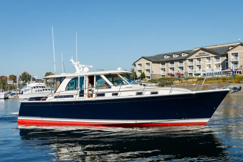 The Image of 2021 Sabre 45 Salon Express yacht cruising near waterfront buildings. - 1