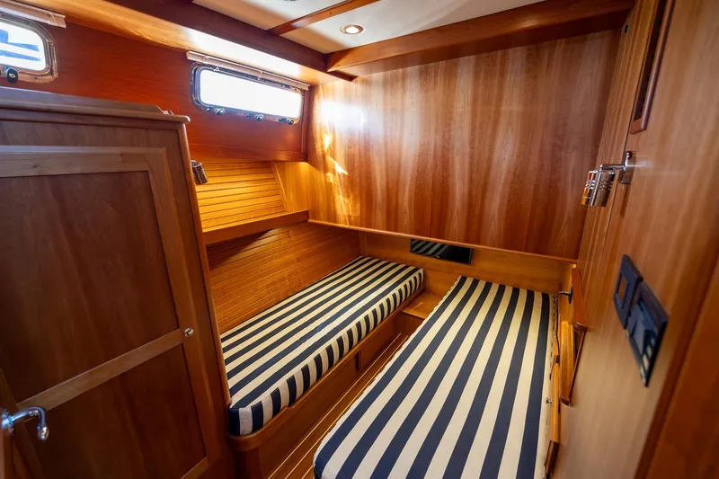 Slide: The Image of 2021 Sabre 45 Salon Express cabin with striped bedding and wooden interior. - 27