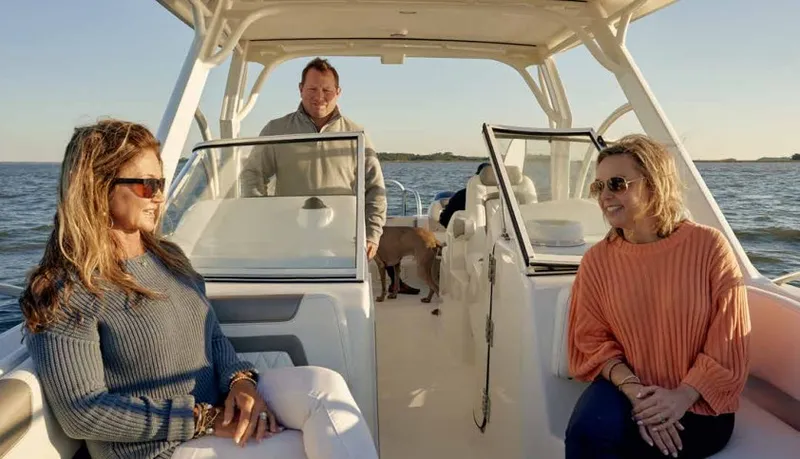 Slide: The Image of Three people sit on a boat cruising on calm waters. The sky is clear. - 24