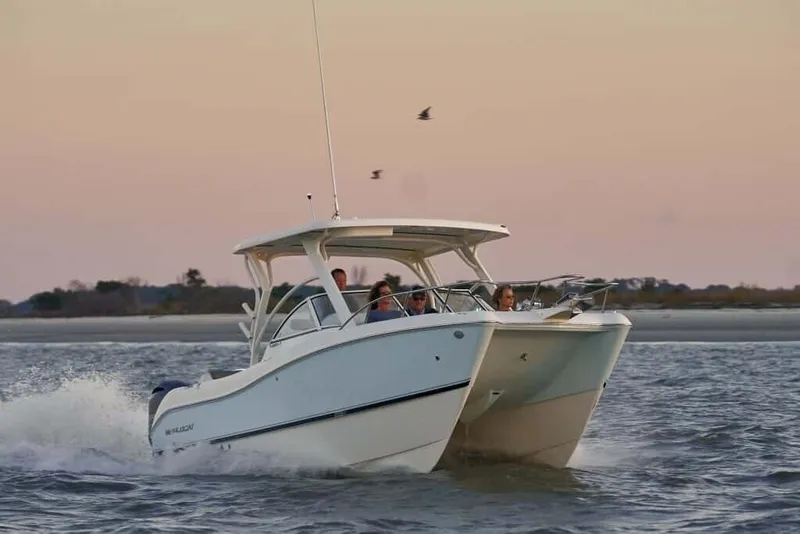 Slide: The Image of A 2013 World Cat 255 DC cruising on the water at sunset. Several people are on board. - 2