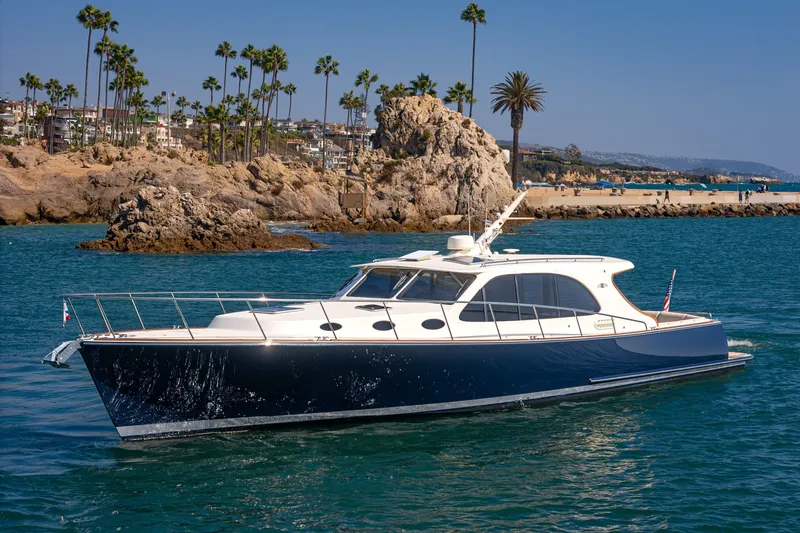Slide: The Image of 2019 Palm Beach Motor Yachts Express cruising near rocky coastline and palm trees. - 46