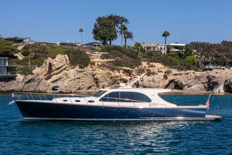Slide: The Image of 2019 Palm Beach Motor Yachts Express cruising near rocky coastline under clear blue sky. - 42
